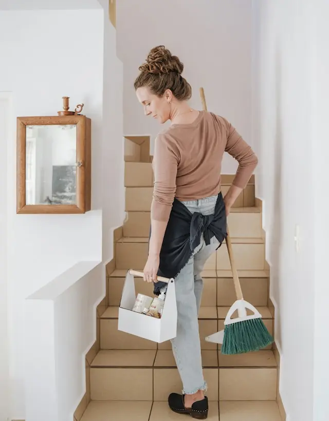 Reinigungskraft mit Putzkorb auf einer Treppe